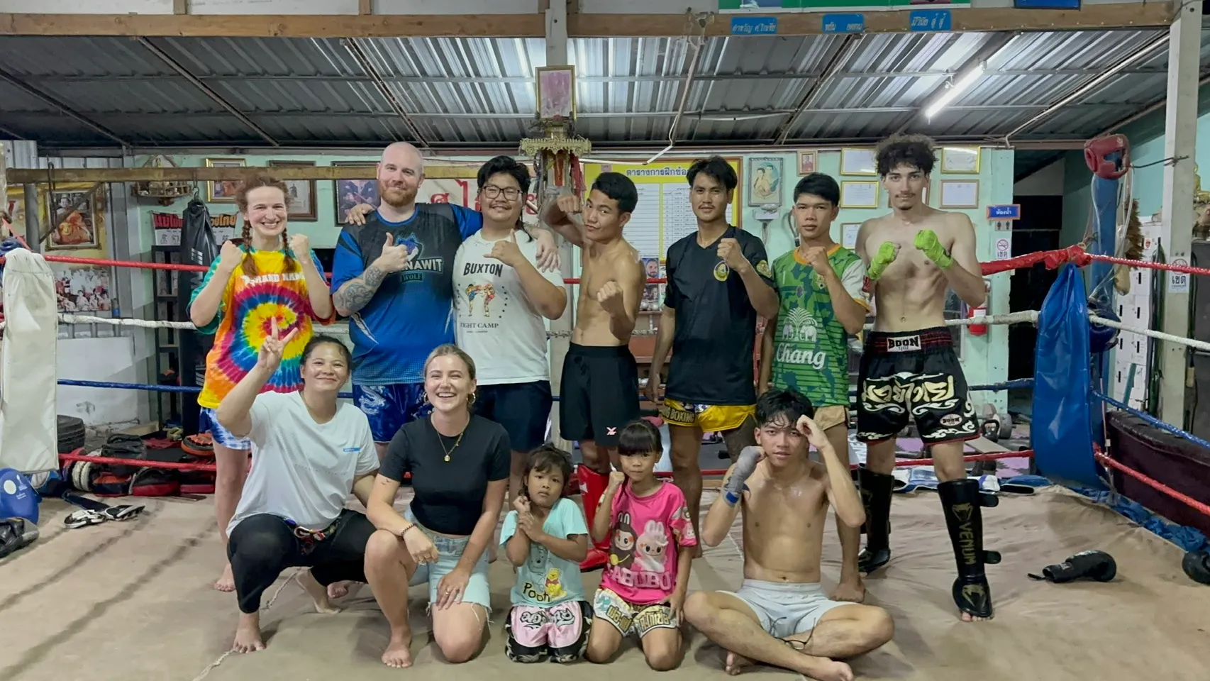 Guests from abroad, local fighters, children and trainers posing in guard together in the Suwanno ring
