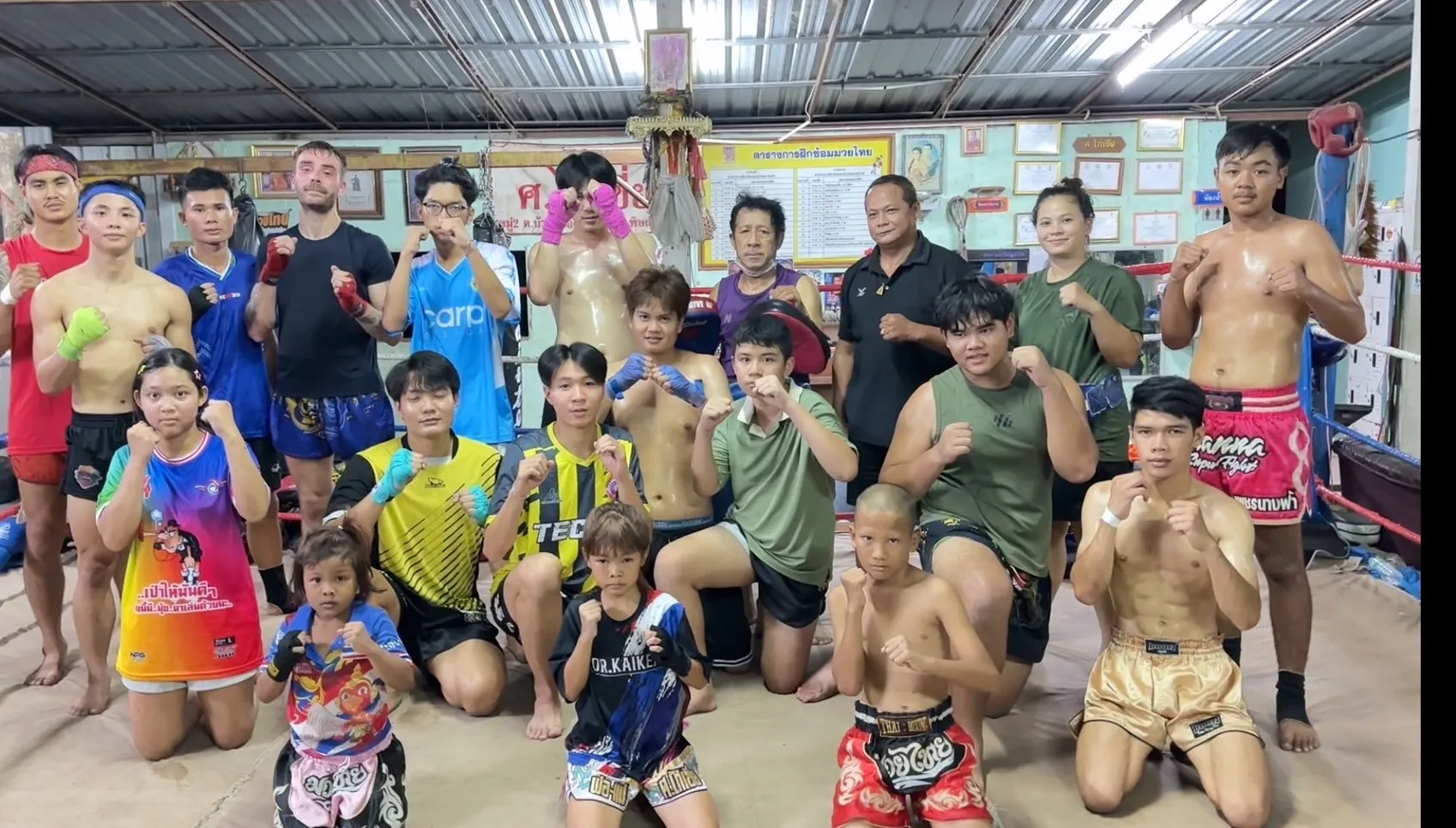 Suwanno fighters, students and coaches of all ages posing in guard inside the camp ring